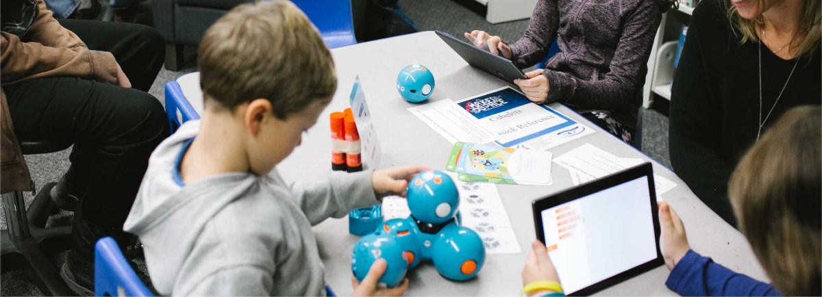 Children sitting at table with the Dash and Dot robotics.